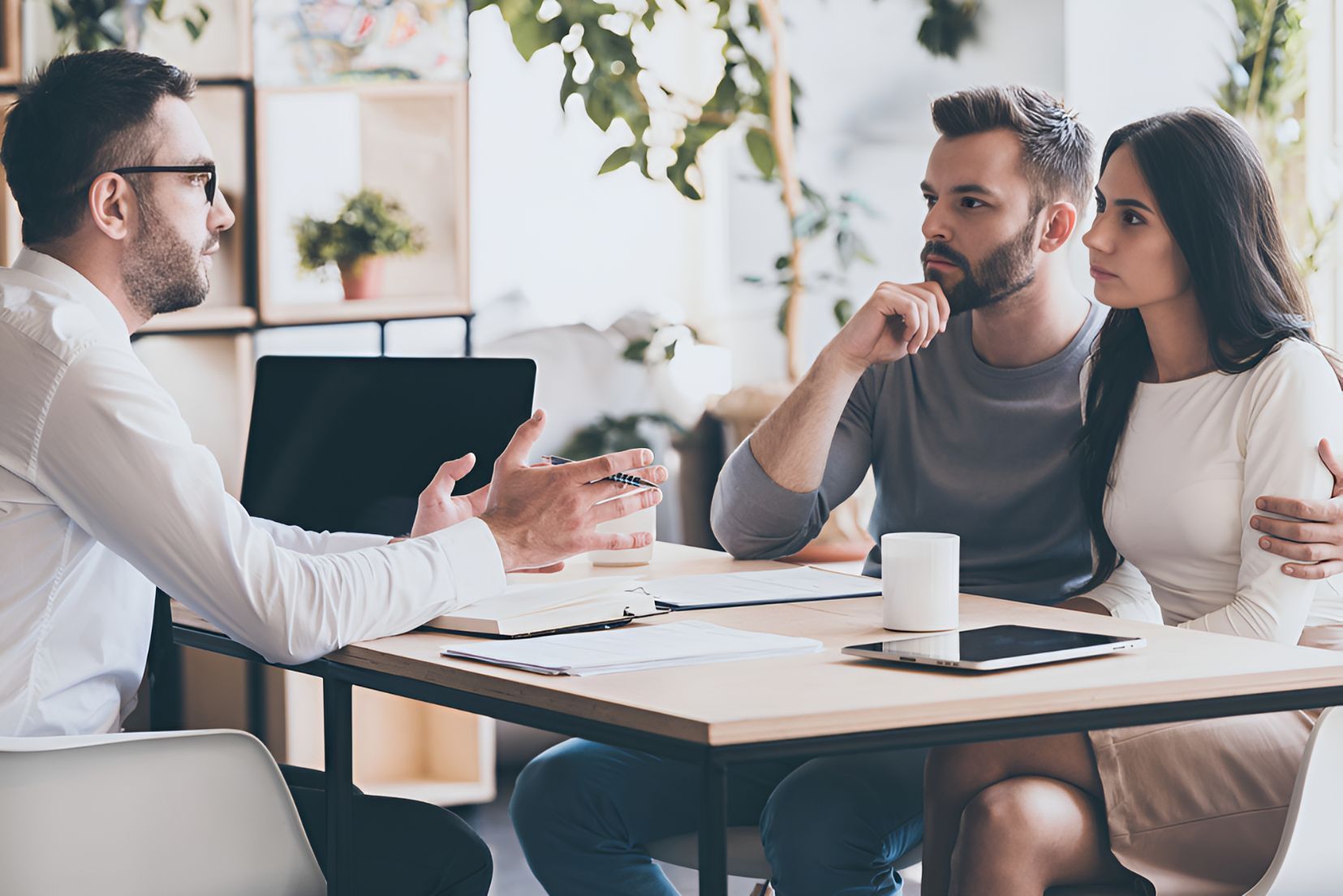 A Man Is Sitting At A Table Talking To A Couple — Grant Finance Solutions In Toowoomba, QLD