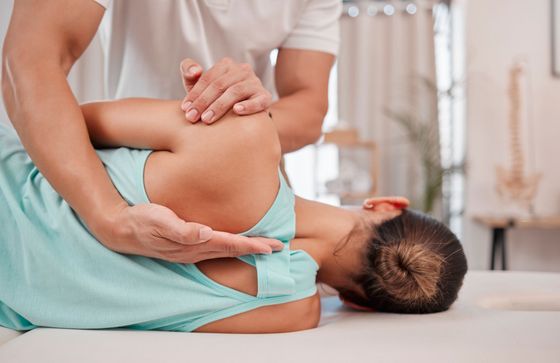 A woman is laying on a bed getting a massage from a man.