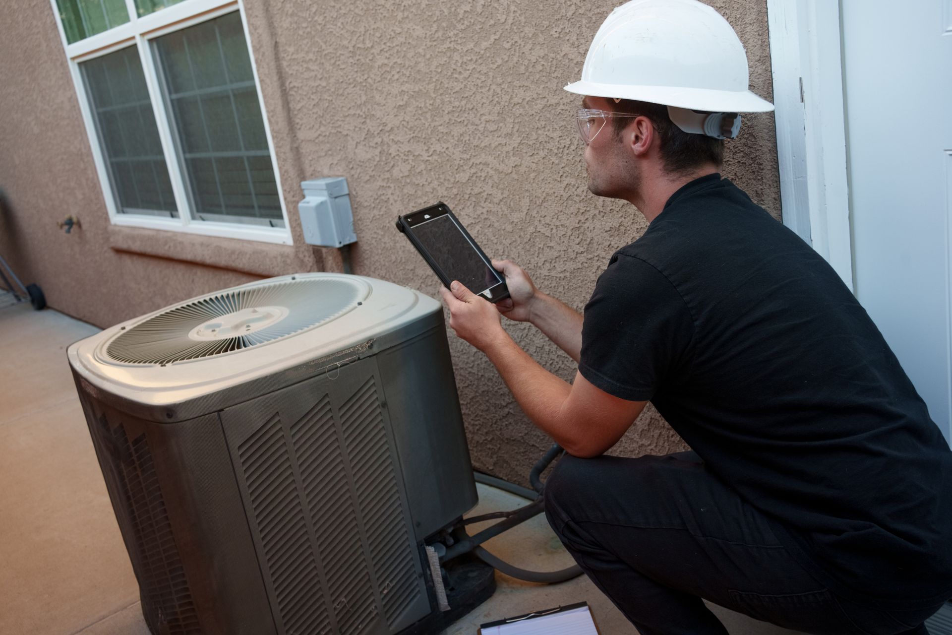 A technician from TruTek Air Conditioning & Heating LLC performing air conditioning maintenance in G