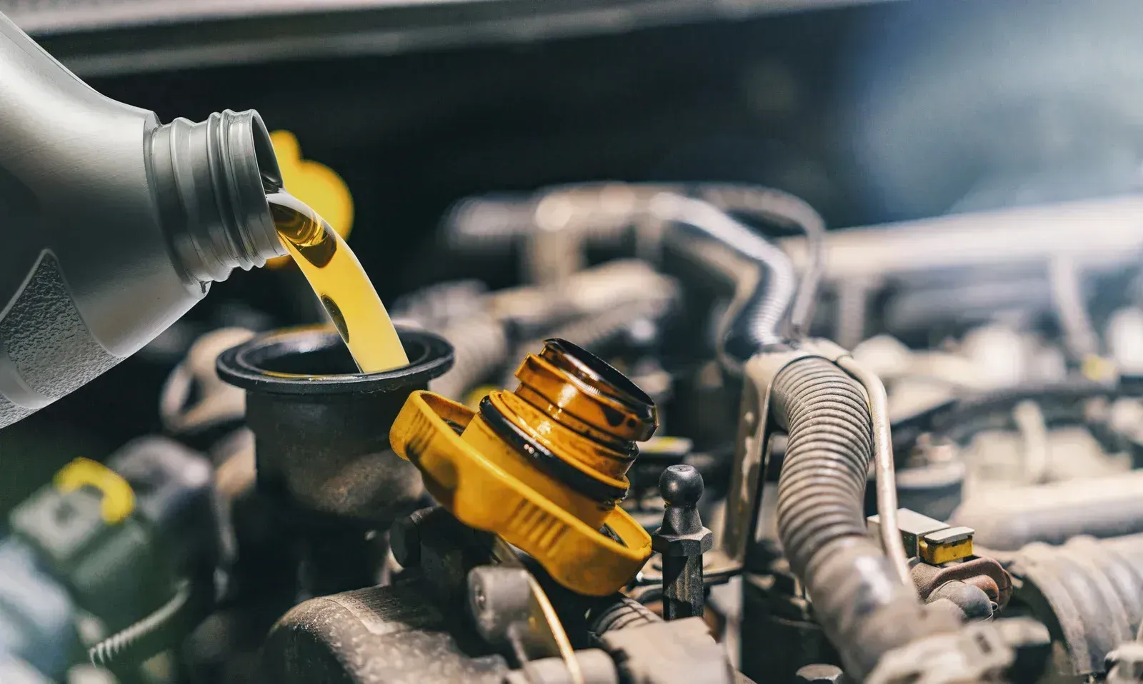 A person is pouring oil into a car engine.