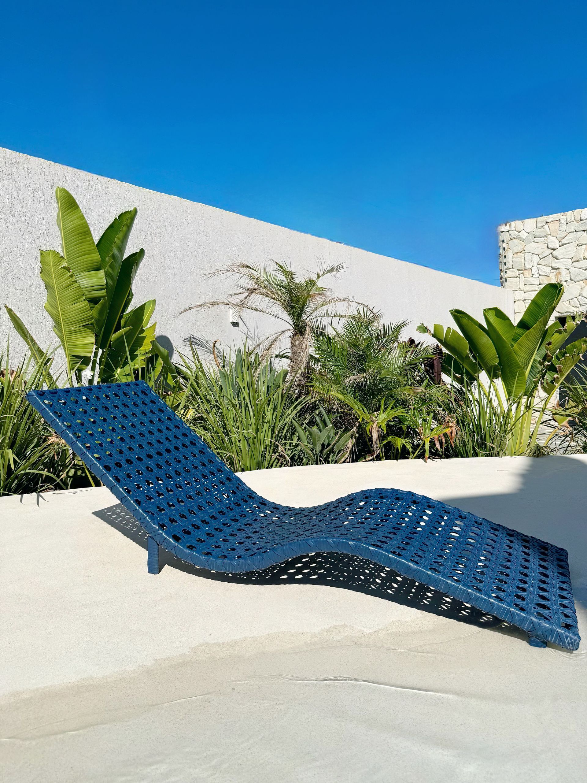 Uma espreguiçadeira azul está ao lado de uma piscina.