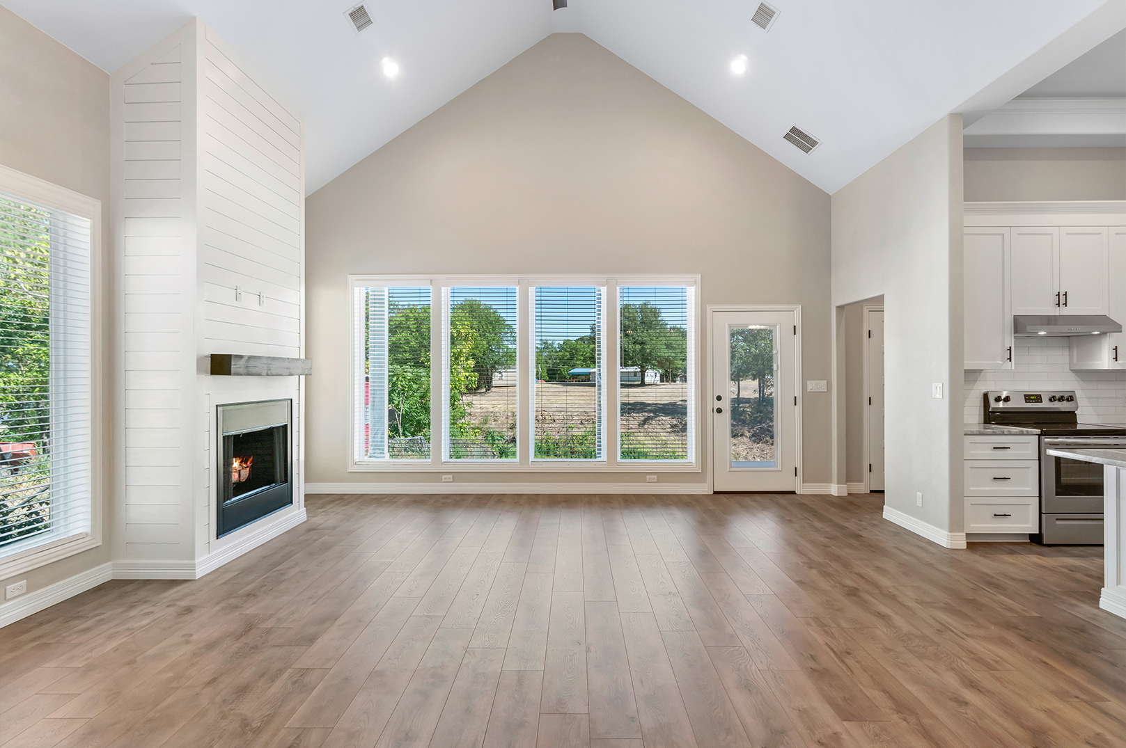 An empty living room with a fireplace and lots of windows.