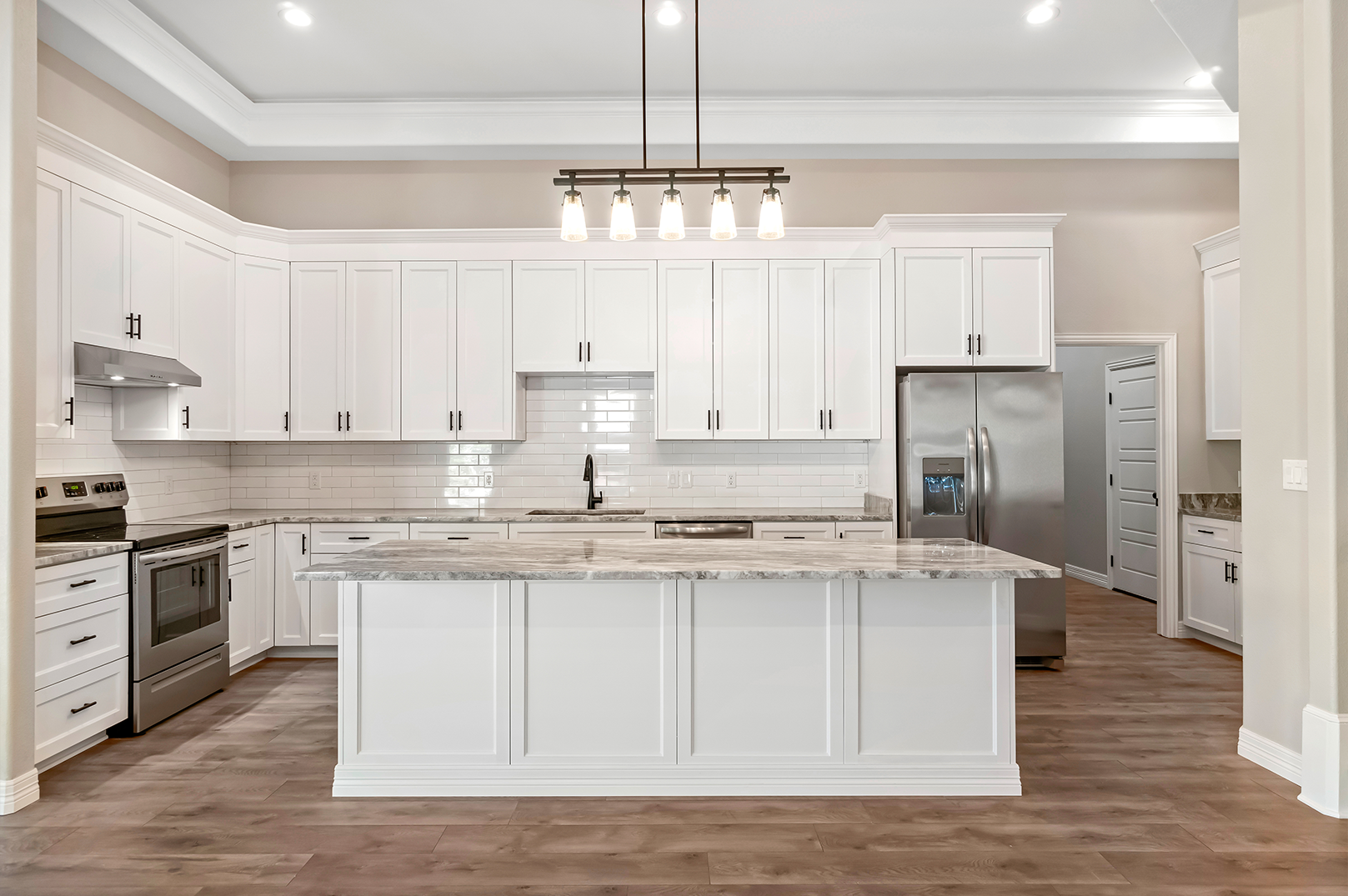 A kitchen with white cabinets , granite counter tops , stainless steel appliances and a large island.
