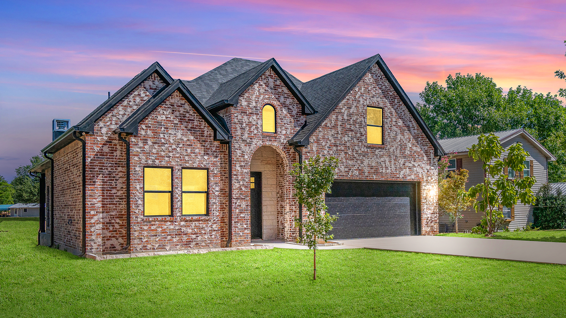 A large brick house is sitting on top of a lush green lawn.