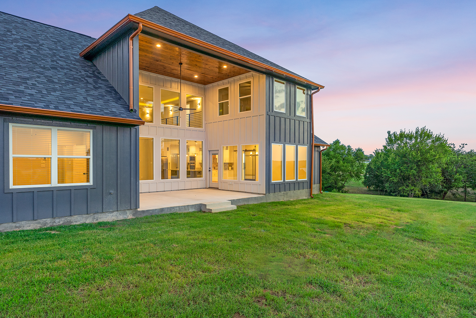 A large house with a lot of windows is sitting on top of a lush green field.
