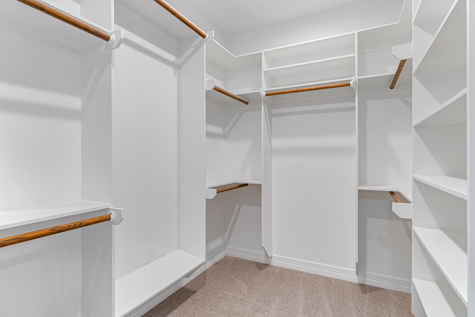 A walk in closet with lots of shelves and clothes racks.