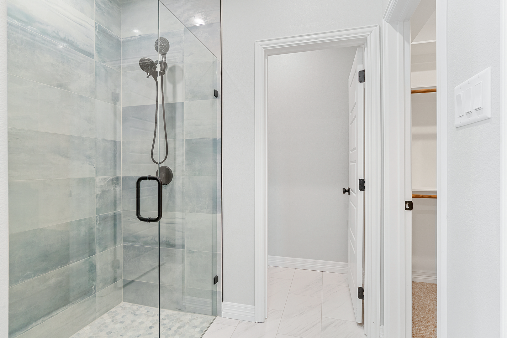 A bathroom with a walk in shower with a glass door.