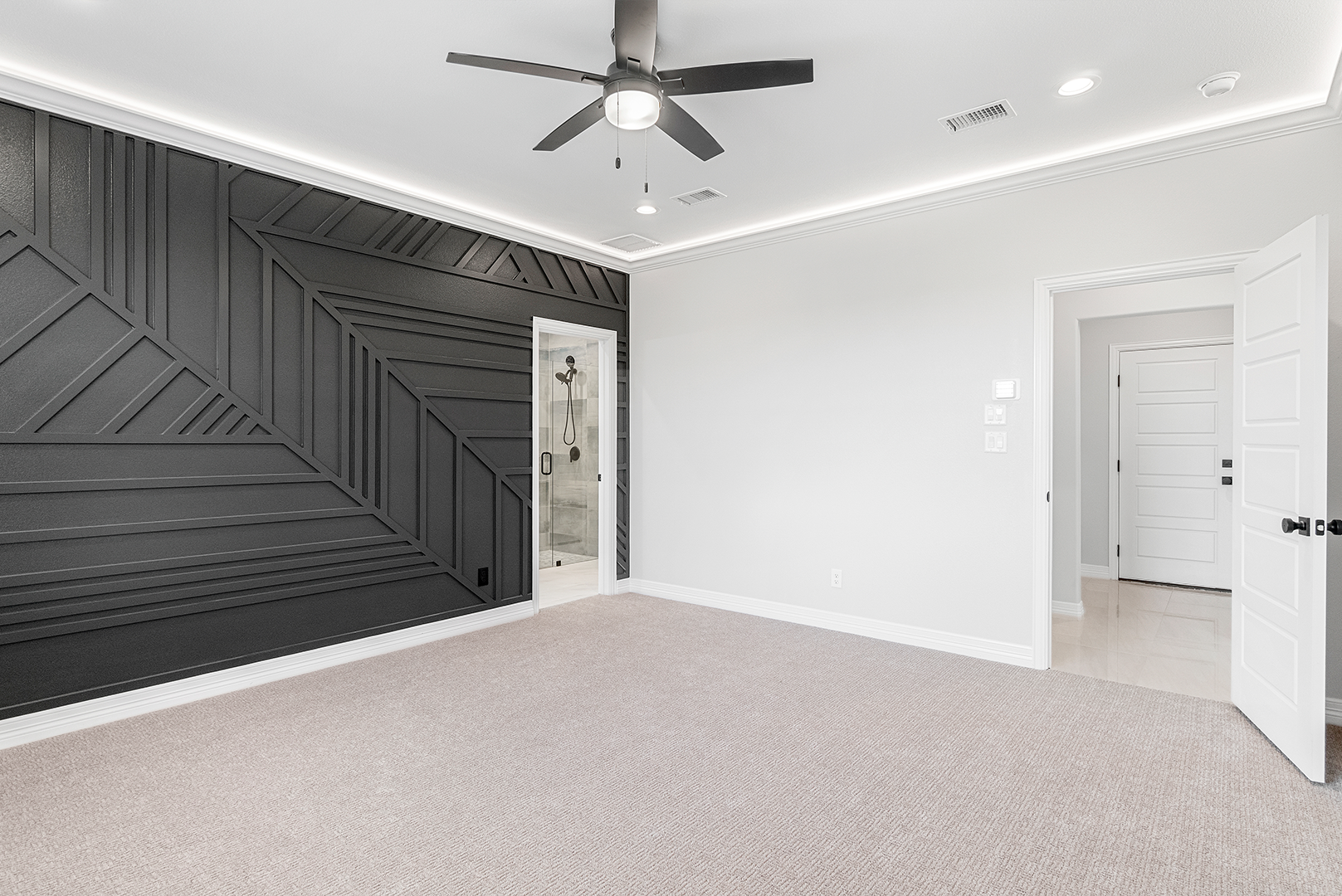 An empty room with a ceiling fan and a black wall.