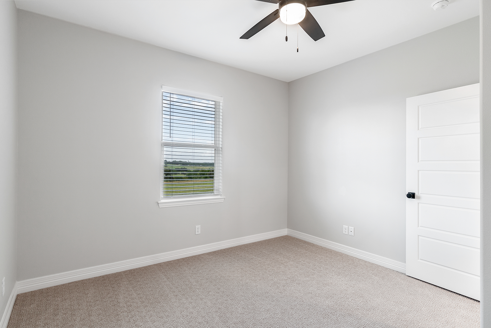 An empty bedroom with a ceiling fan and a window.