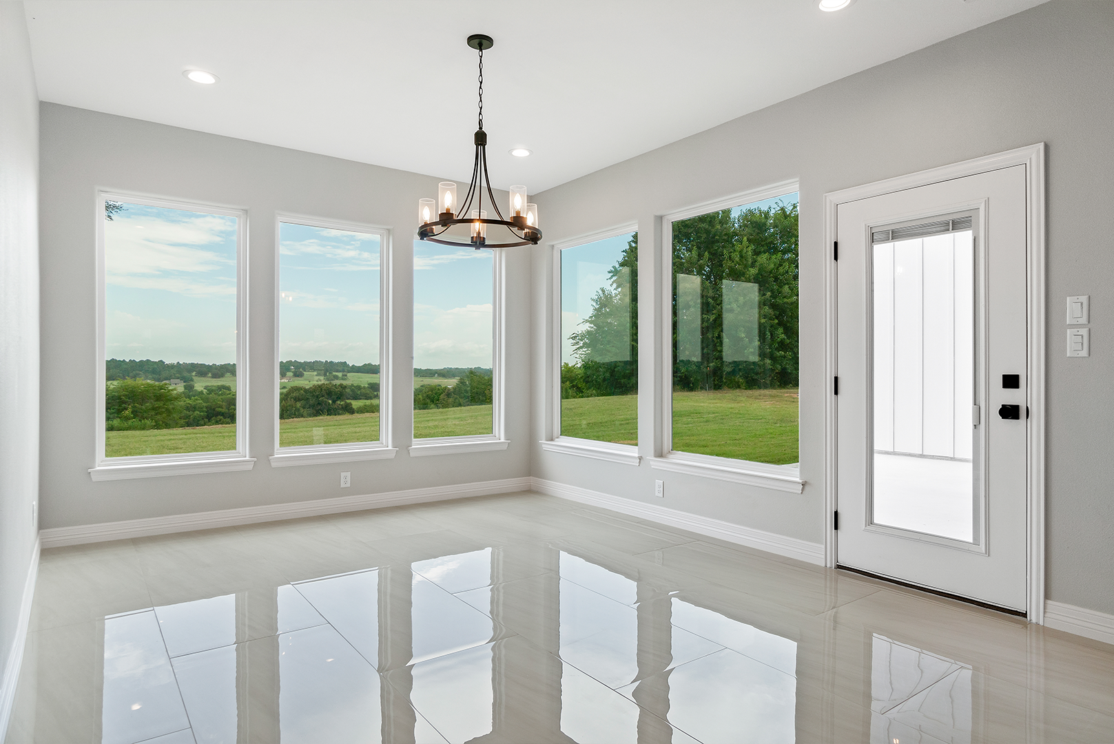 An empty room with a lot of windows and a door.