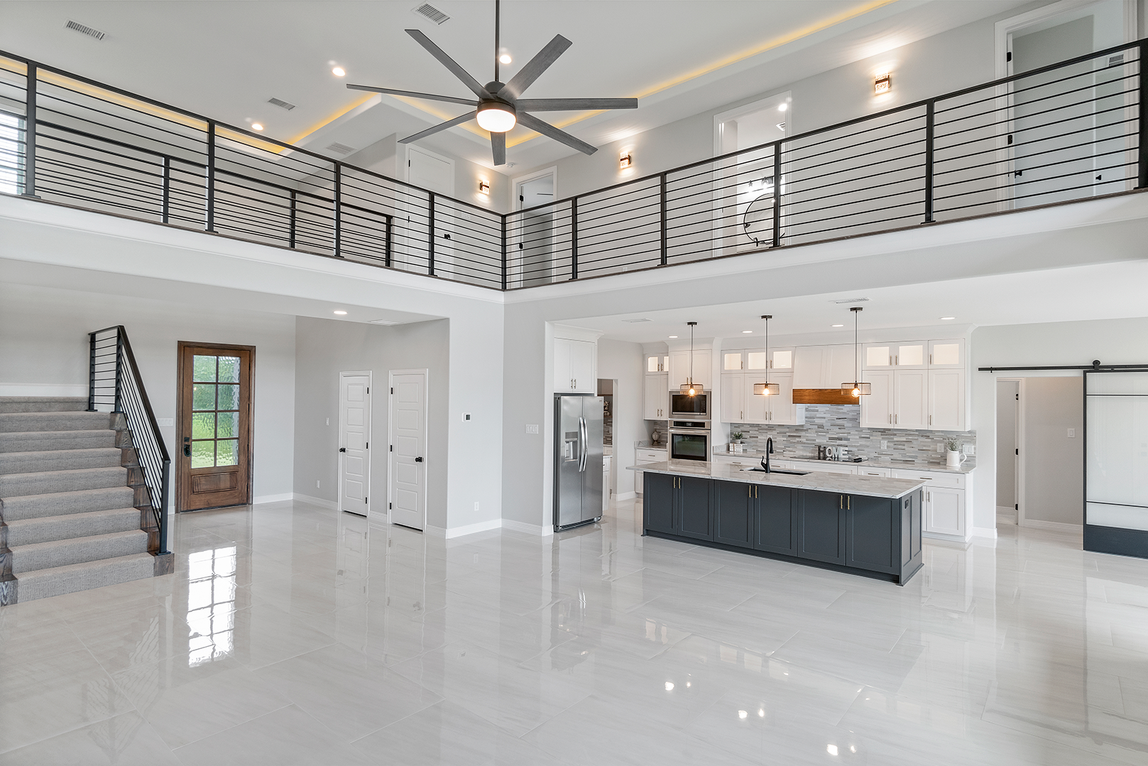 A large empty kitchen with a balcony and a ceiling fan.