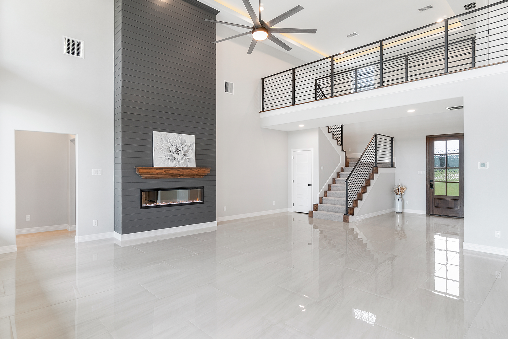A large empty living room with a fireplace and stairs.