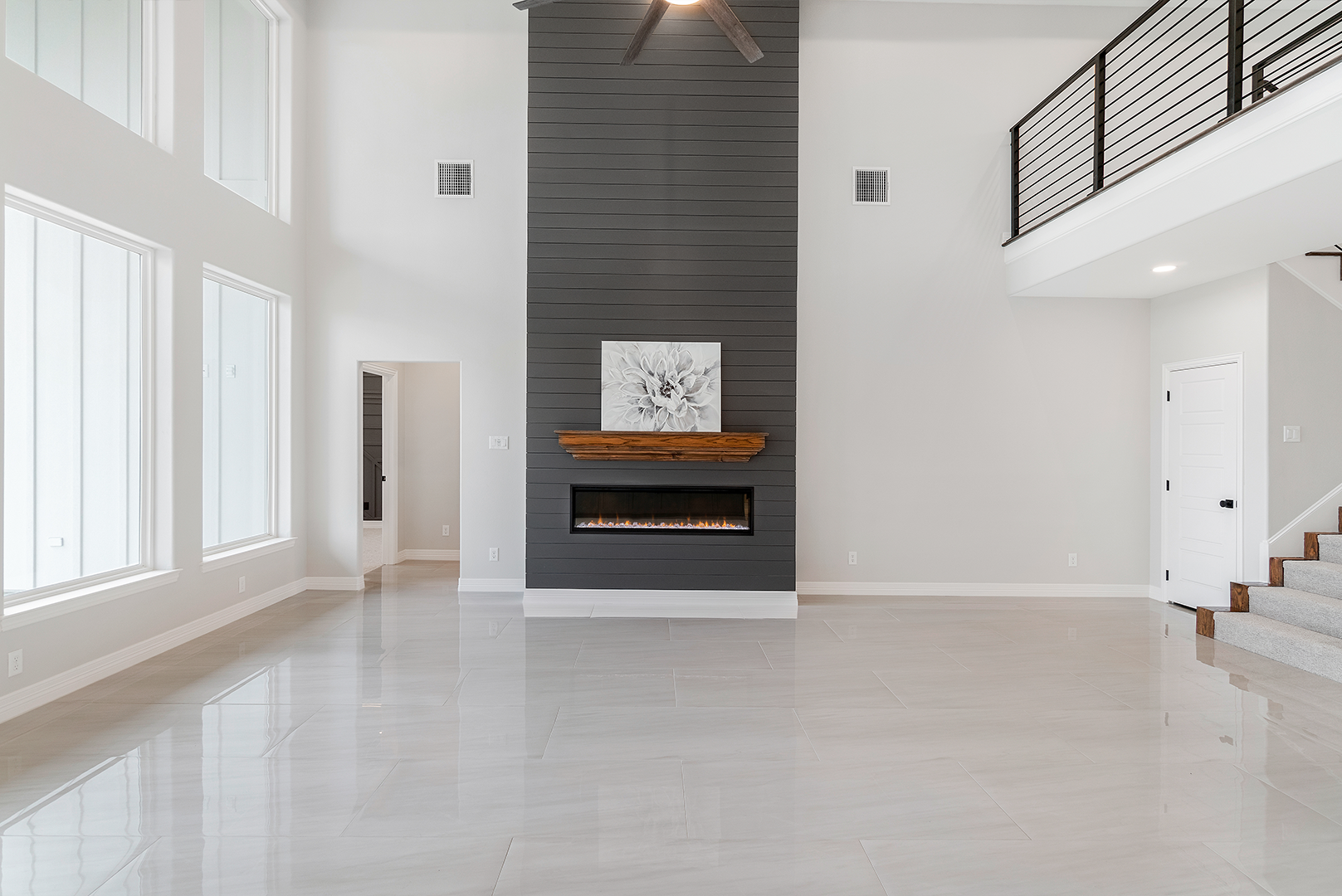 A large empty living room with a fireplace and stairs.