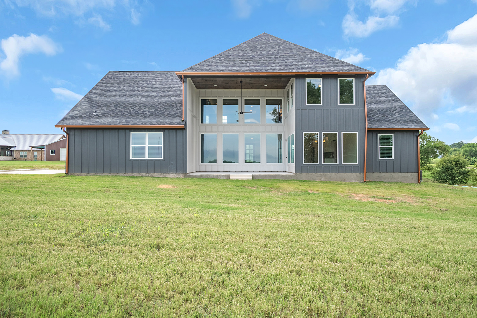 A large house with a lot of windows is sitting on top of a lush green field.