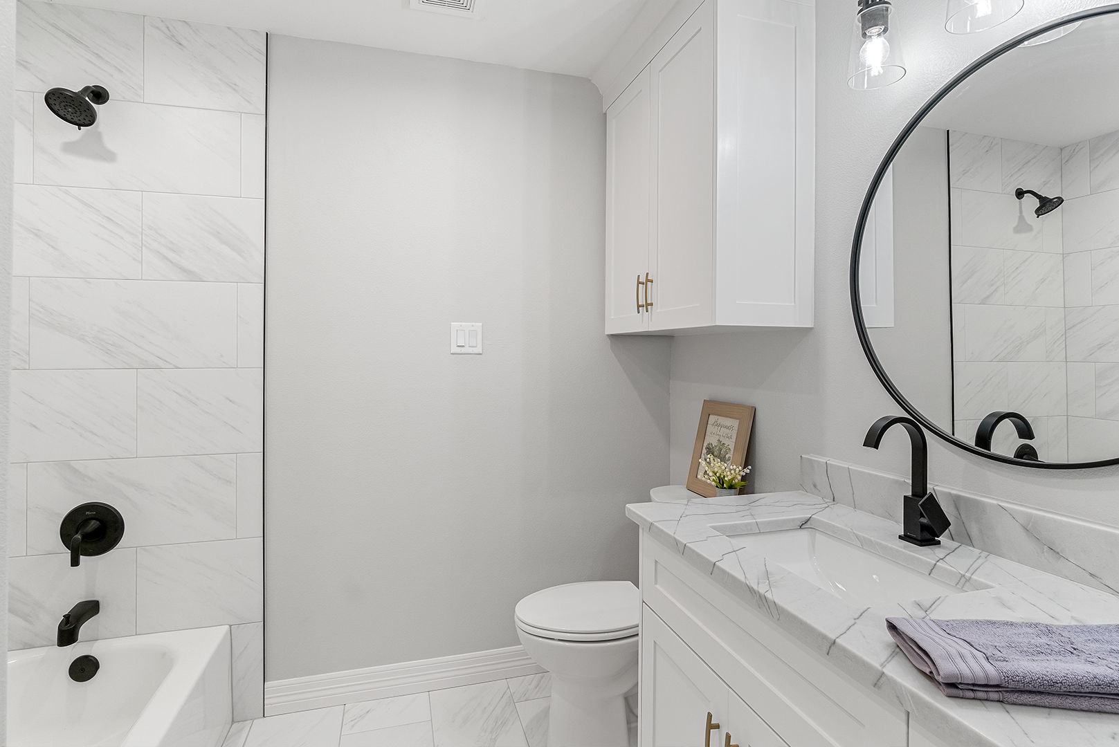 A bathroom with a sink , toilet , shower and mirror.
