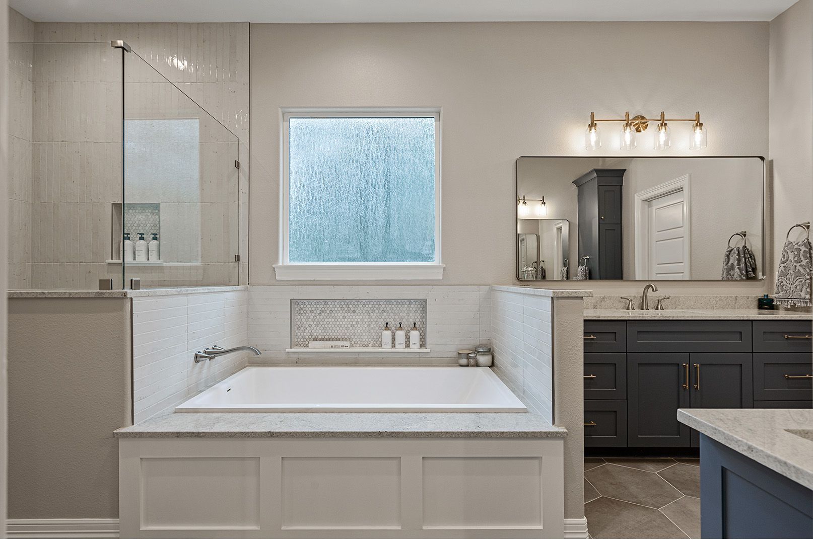 A bathroom with a tub , sink , mirror and window.