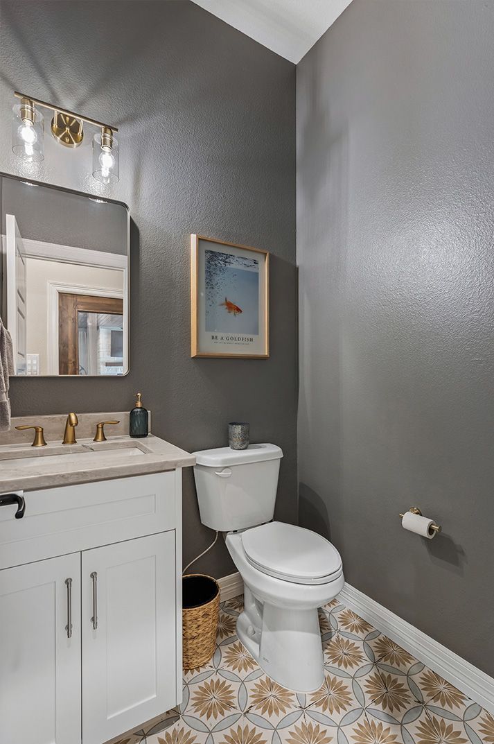 A bathroom with a toilet , sink and mirror.