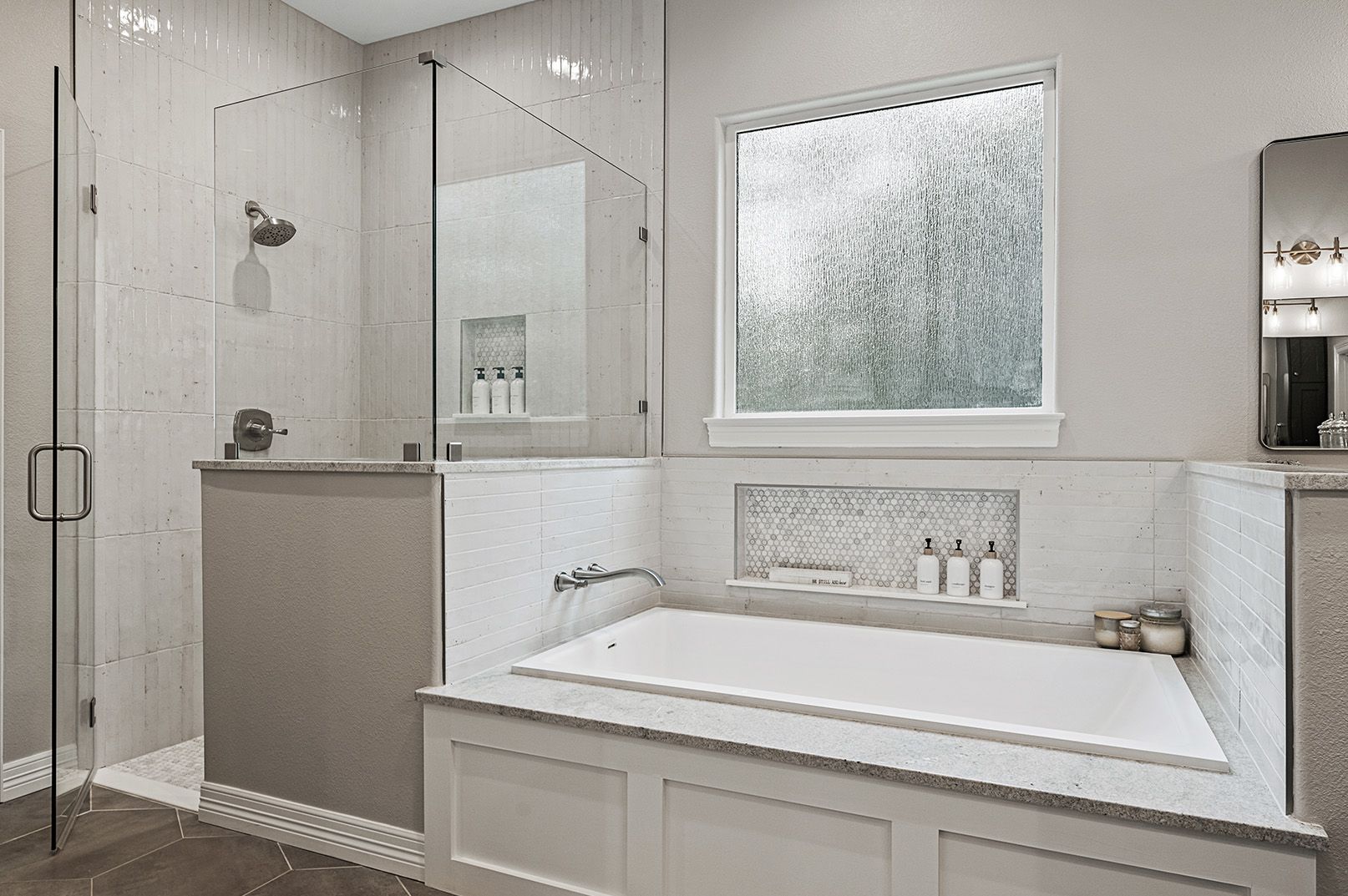 A bathroom with a tub , shower , mirror and window.