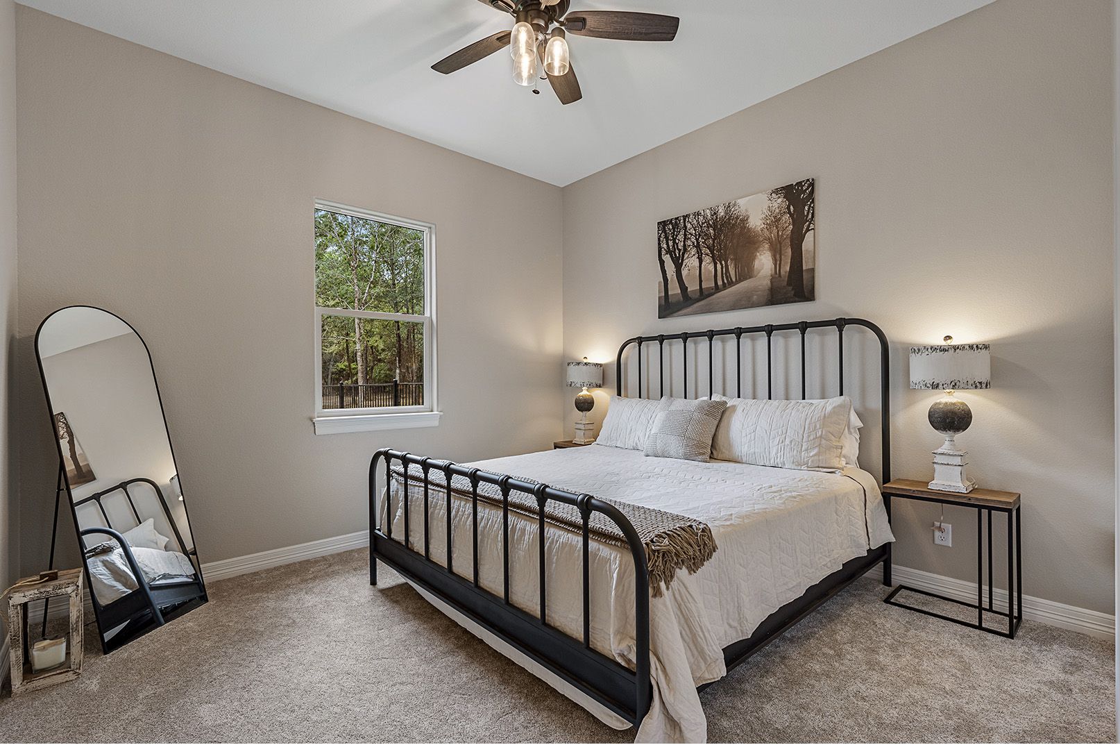A bedroom with a bed , nightstand , mirror and ceiling fan.