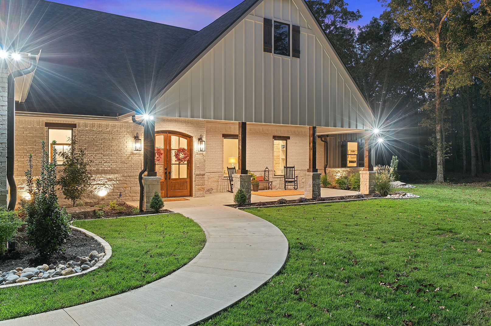 A large house with a porch and a walkway leading to it at night.