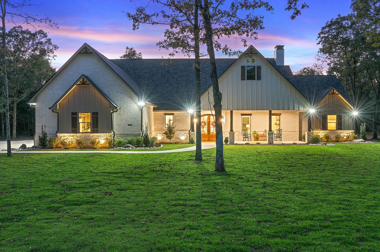 A large house is sitting in the middle of a lush green field.