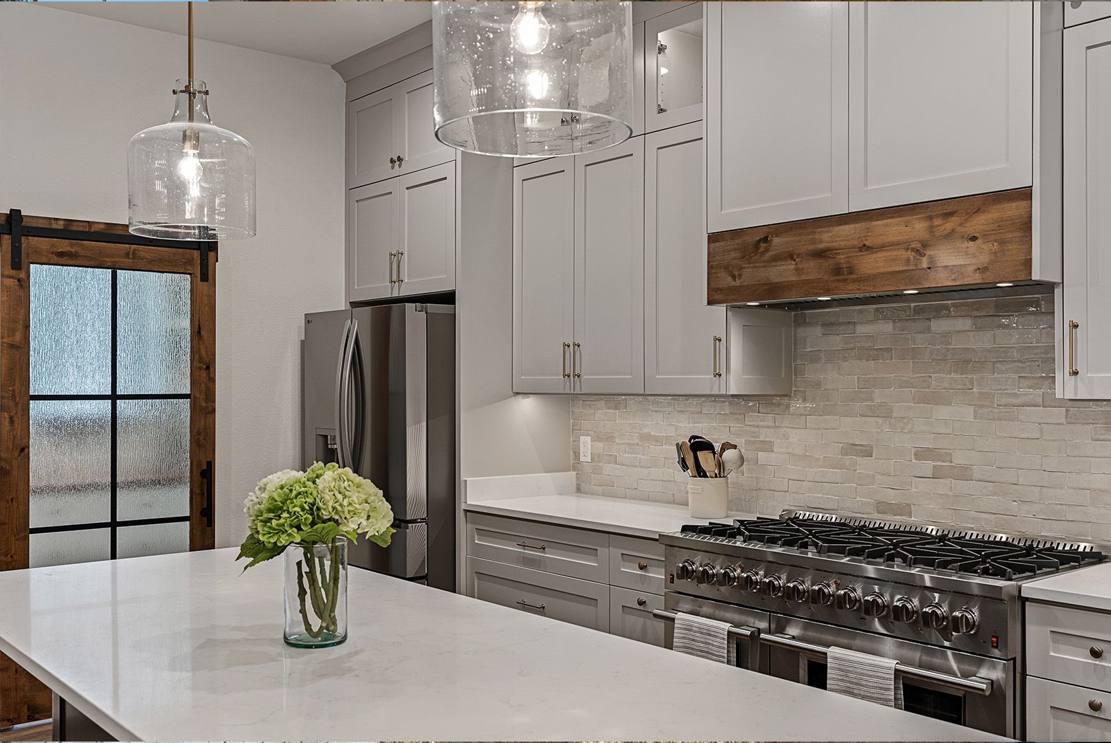 There is a vase of flowers on the counter in the kitchen.