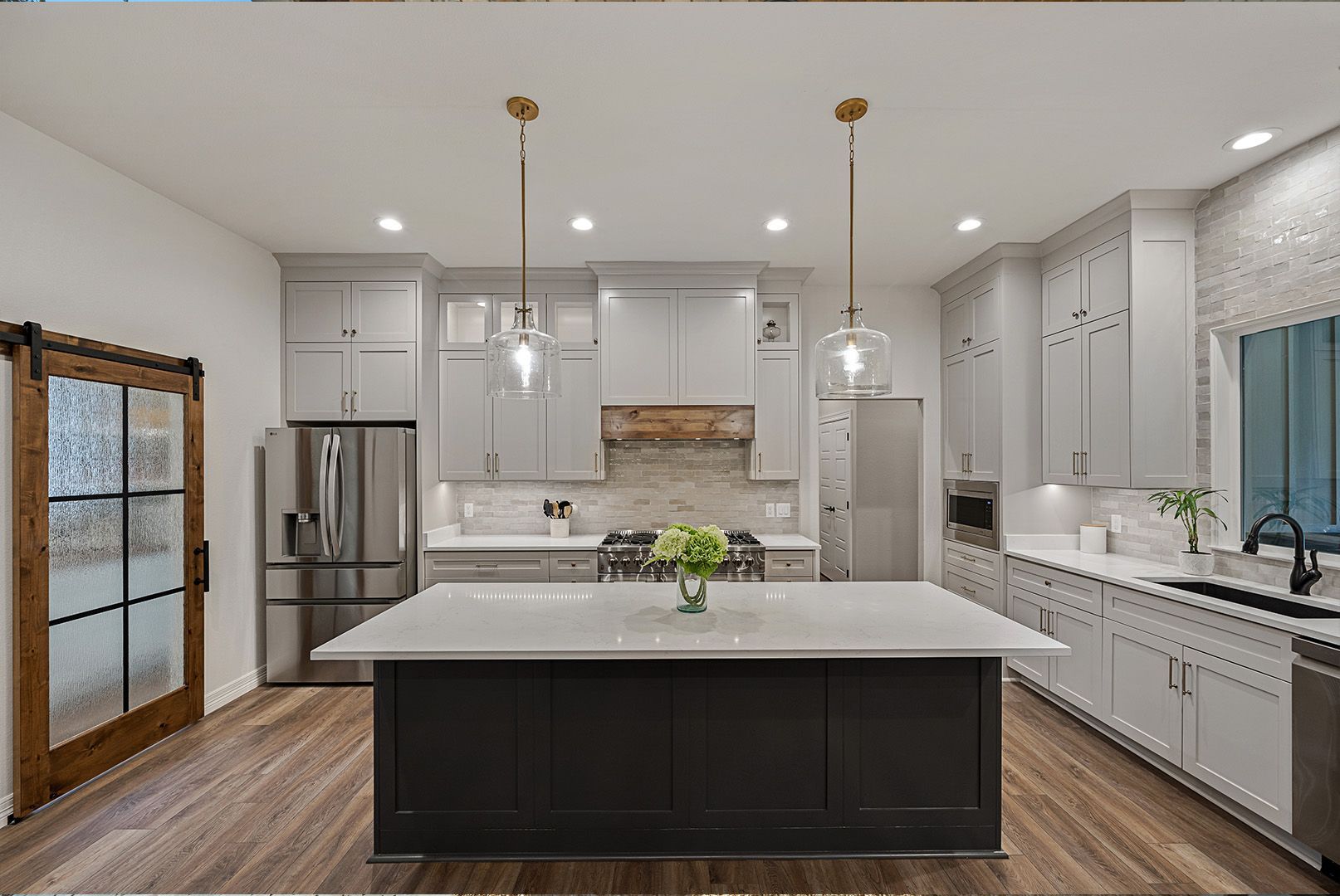 A kitchen with a large island in the middle and stainless steel appliances.