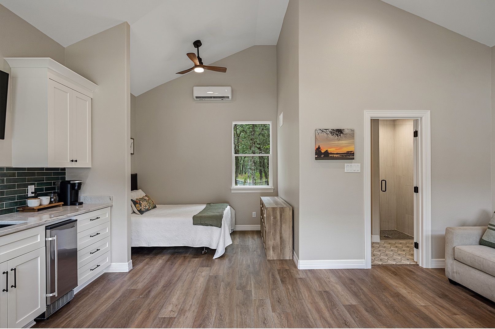 A bedroom with a bed , a kitchen , and a ceiling fan.
