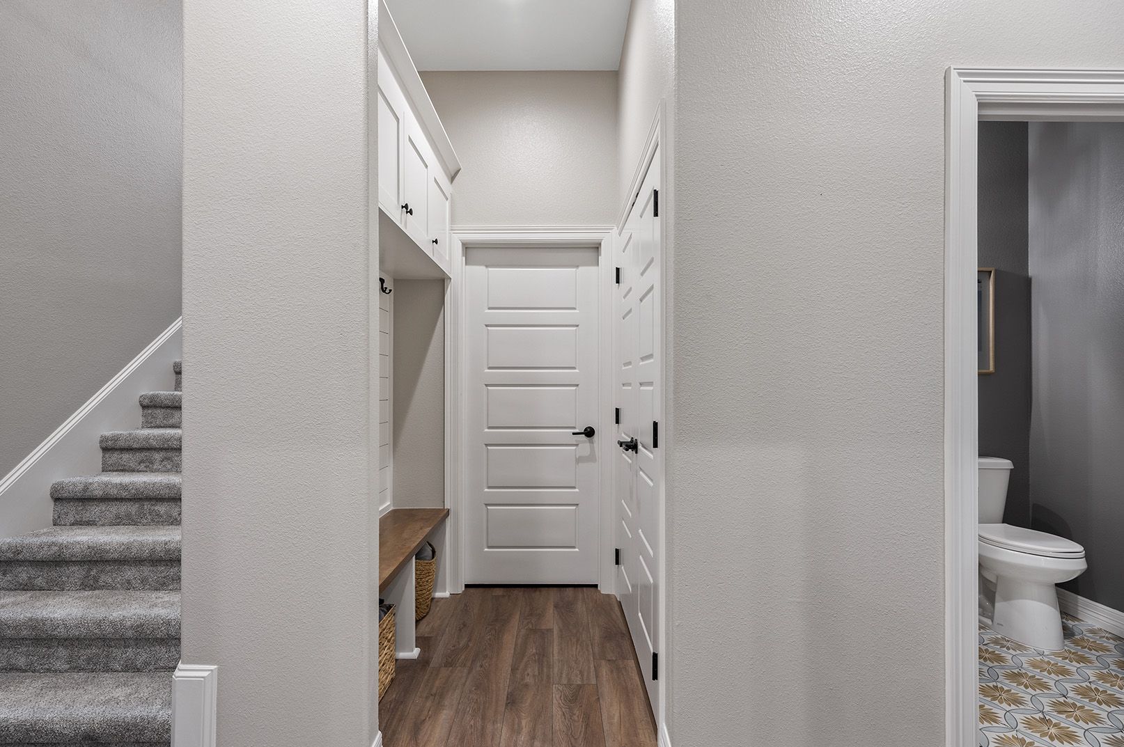 A hallway with stairs and a toilet in a house.