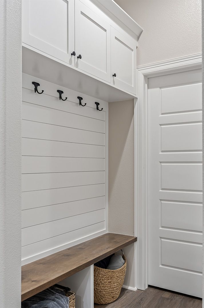 A mud room with a wooden bench and hooks on the wall.