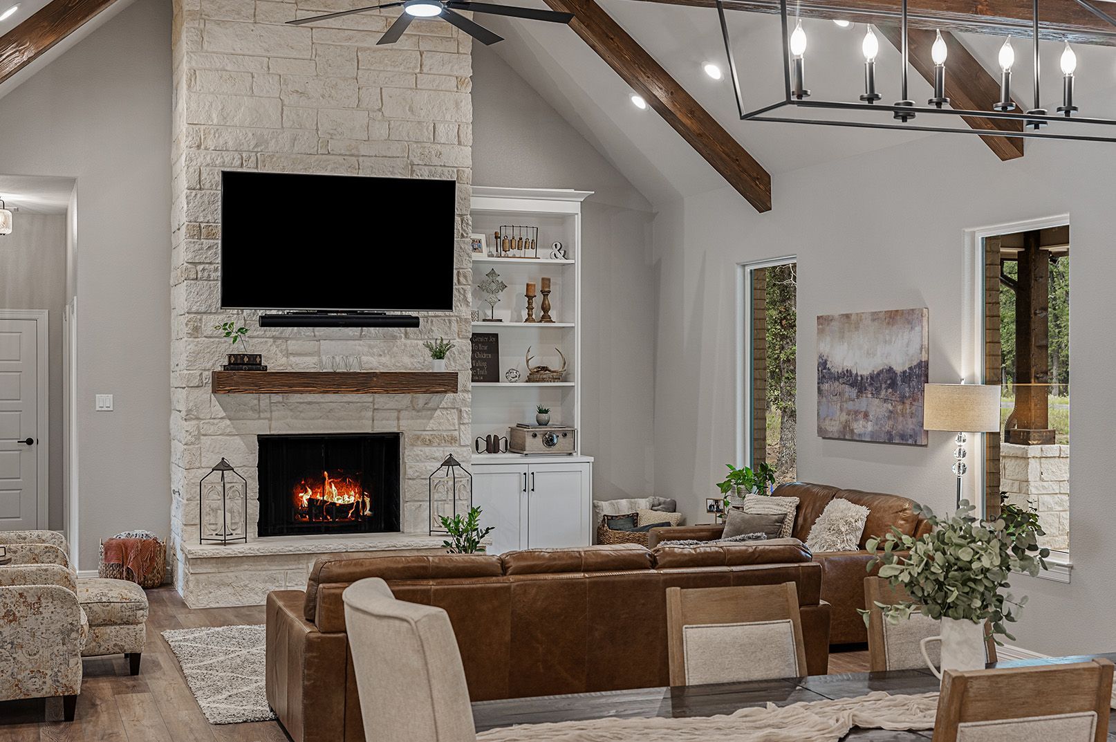 A living room with a fireplace , couch , chairs and a flat screen tv.