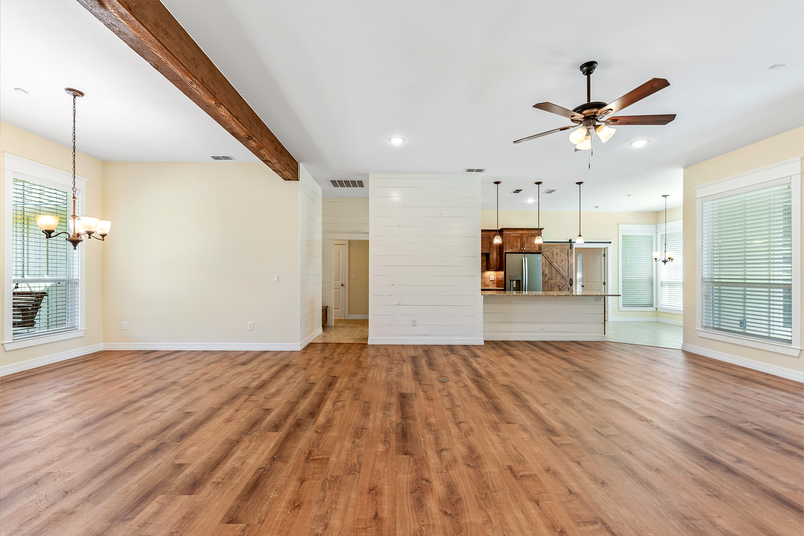 An empty living room with hardwood floors and a ceiling fan.