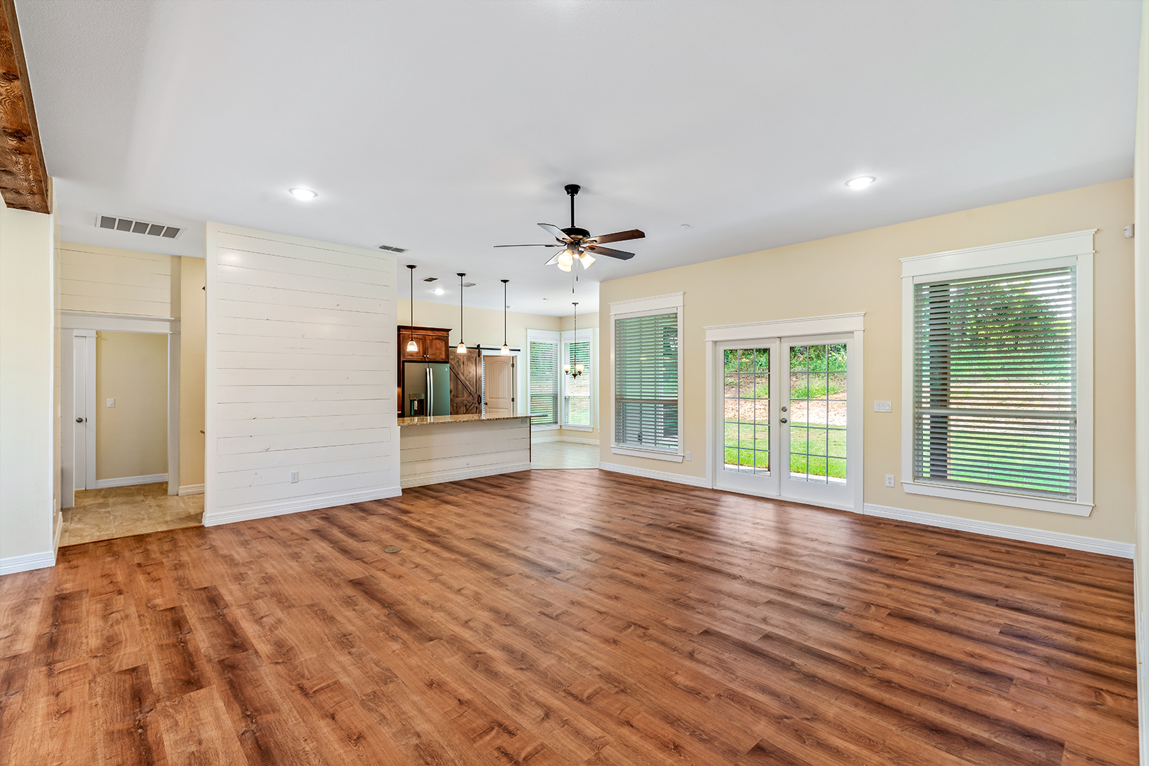 An empty living room with hardwood floors and a ceiling fan.