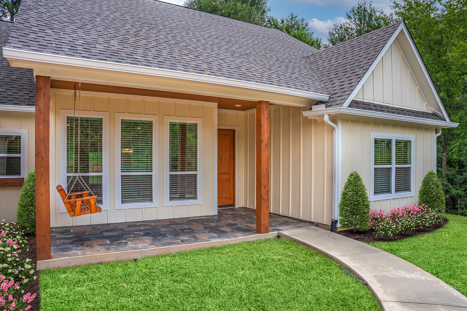 A white house with a porch and a swing on it.
