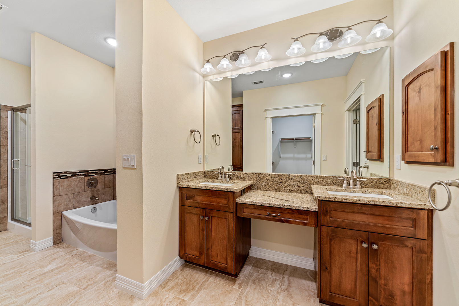 A bathroom with two sinks , a tub and a mirror.