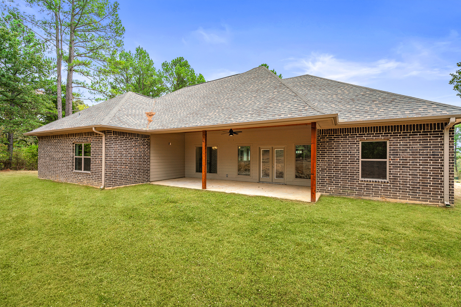 The back of a house with a large lawn in front of it.