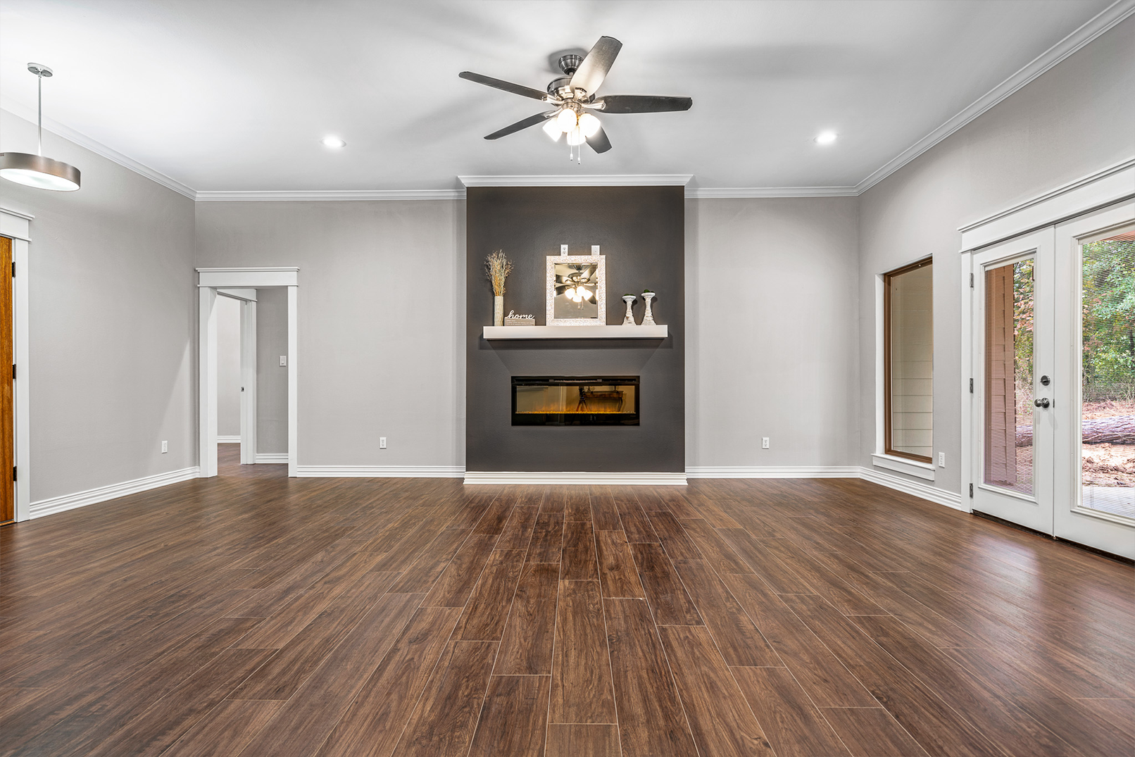 An empty living room with a fireplace and a ceiling fan