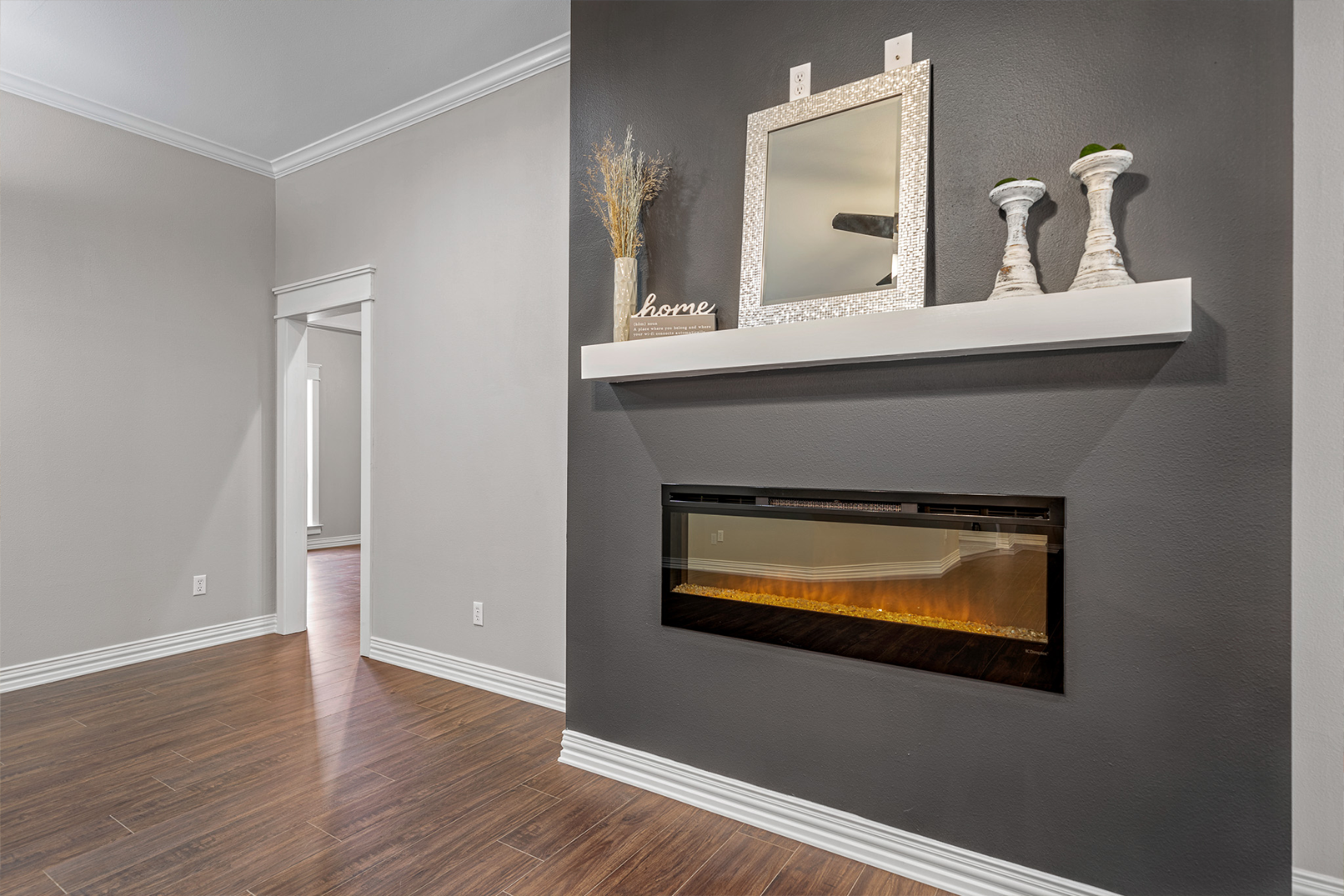An empty living room with a fireplace and a shelf.