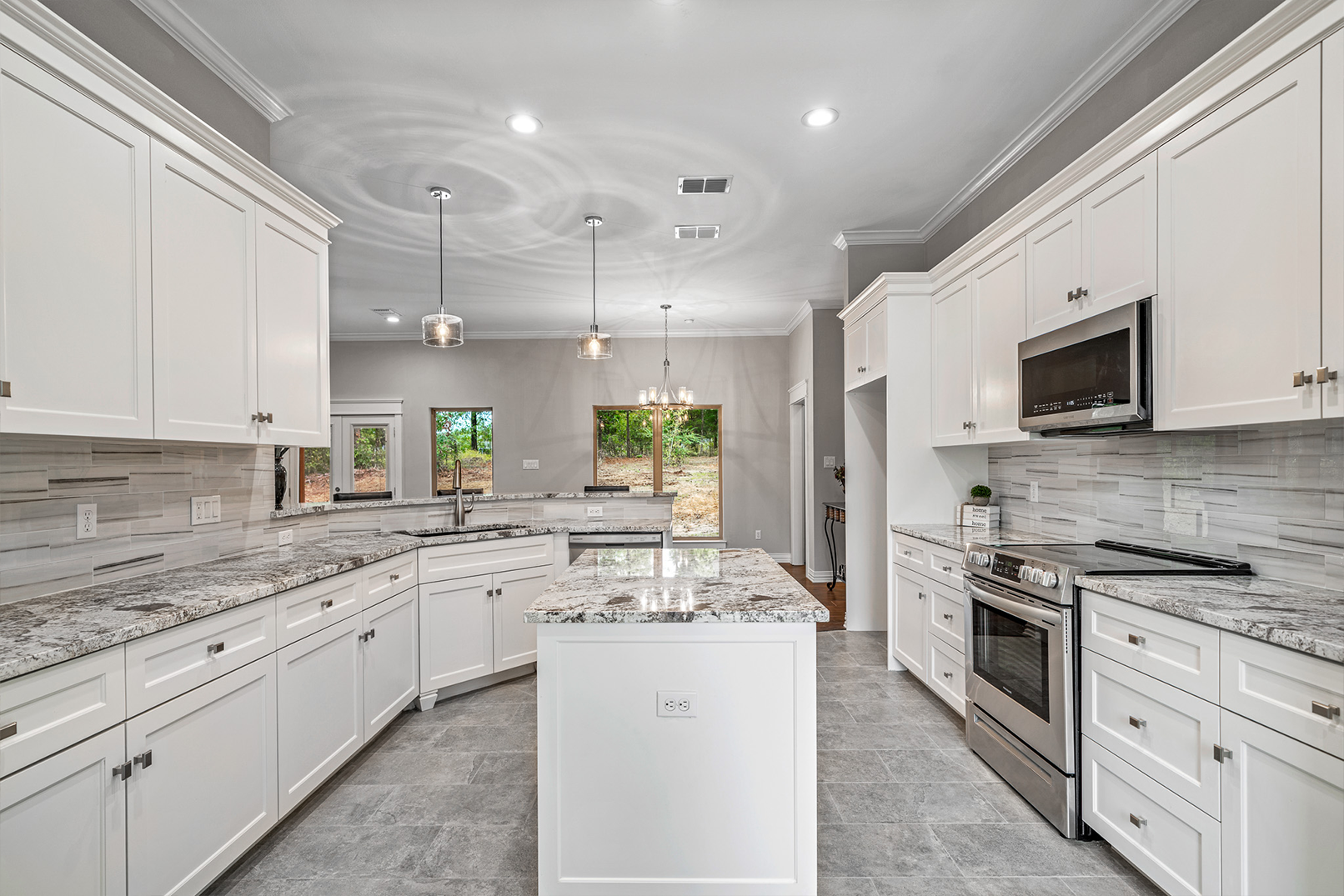 A kitchen with white cabinets , granite counter tops , stainless steel appliances and a large island.