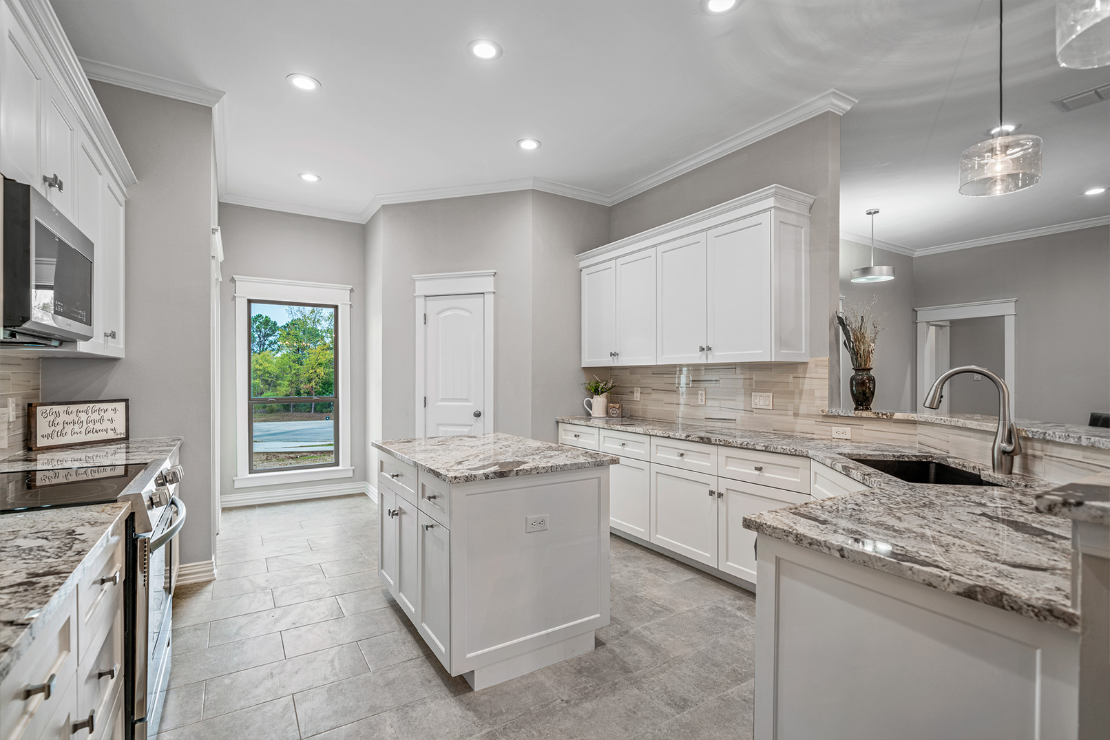 A kitchen with white cabinets and granite counter tops.