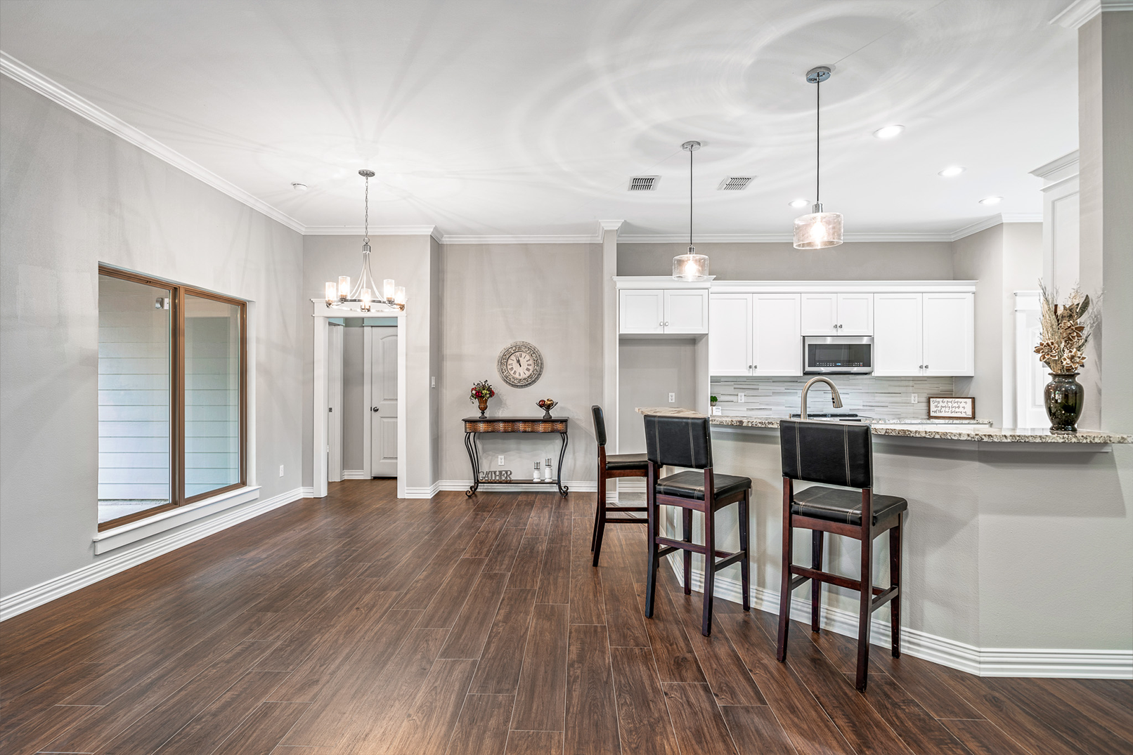 A kitchen and dining room in a house with hardwood floors and white cabinets.