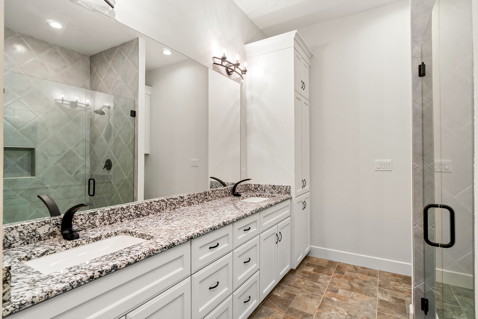 A bathroom with two sinks , a shower and a large mirror.