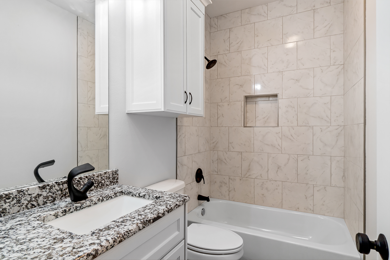 A bathroom with a sink , toilet , tub and mirror.