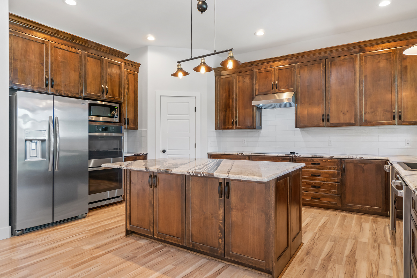 A kitchen with wooden cabinets , stainless steel appliances , and a large island.