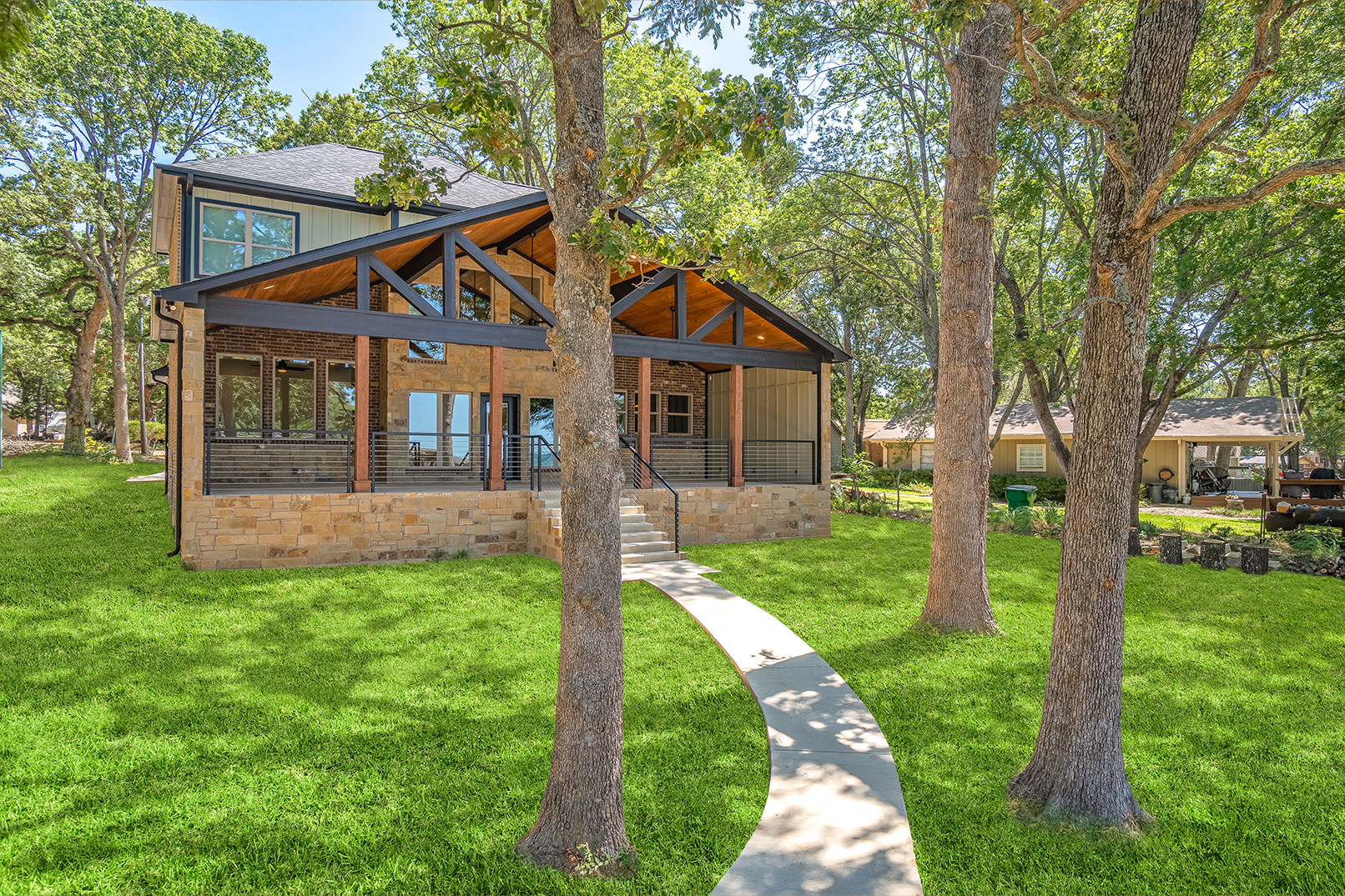 A house with a walkway leading to it is surrounded by trees and grass.