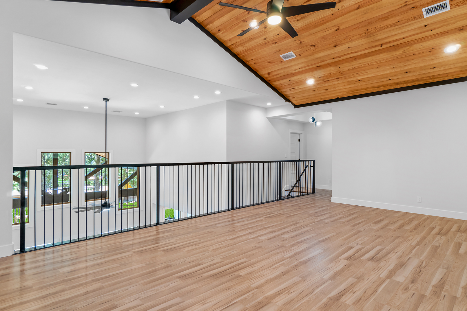 An empty room with hardwood floors and a ceiling fan.