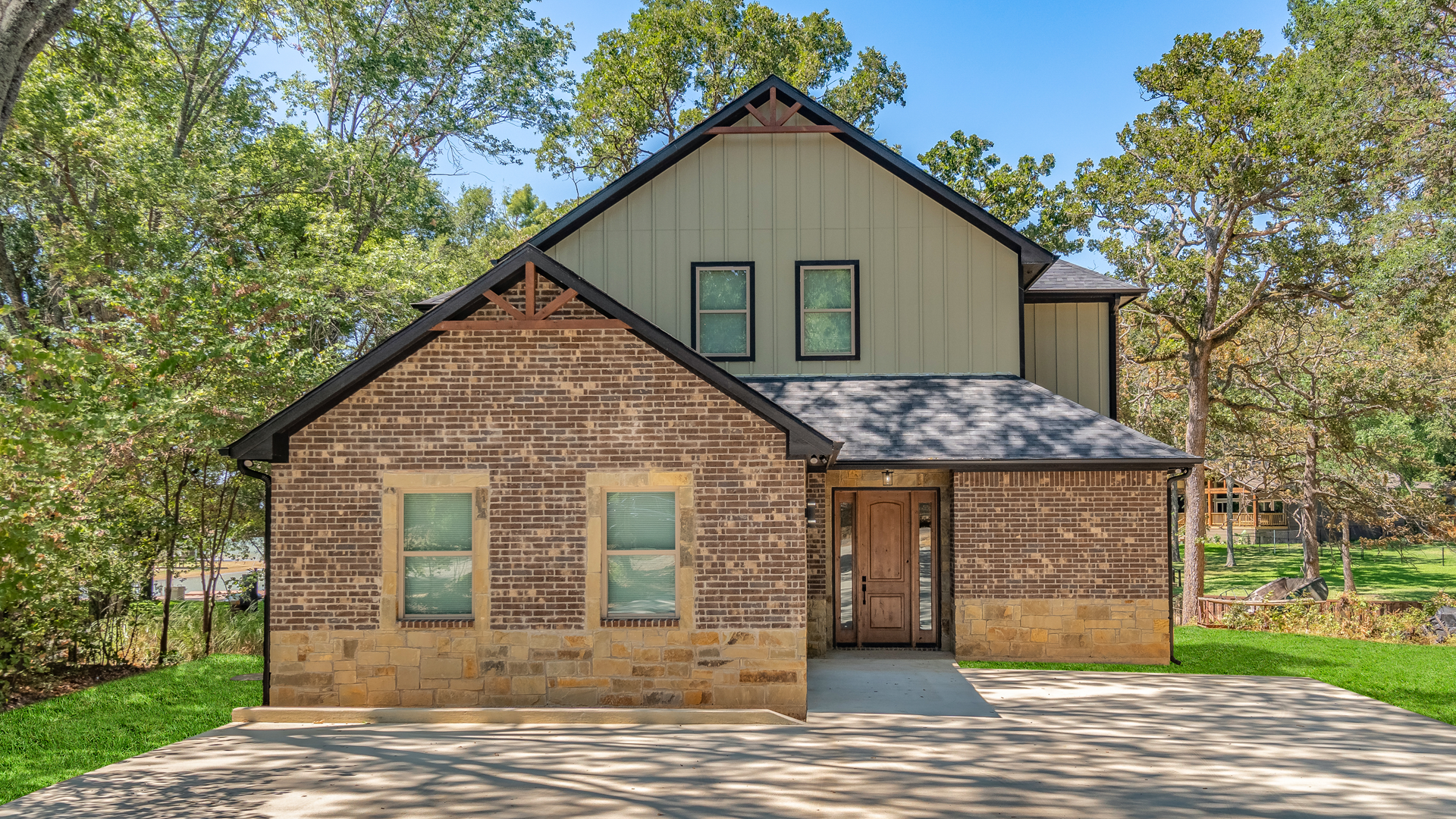 A house with a lot of windows is surrounded by trees and grass.
