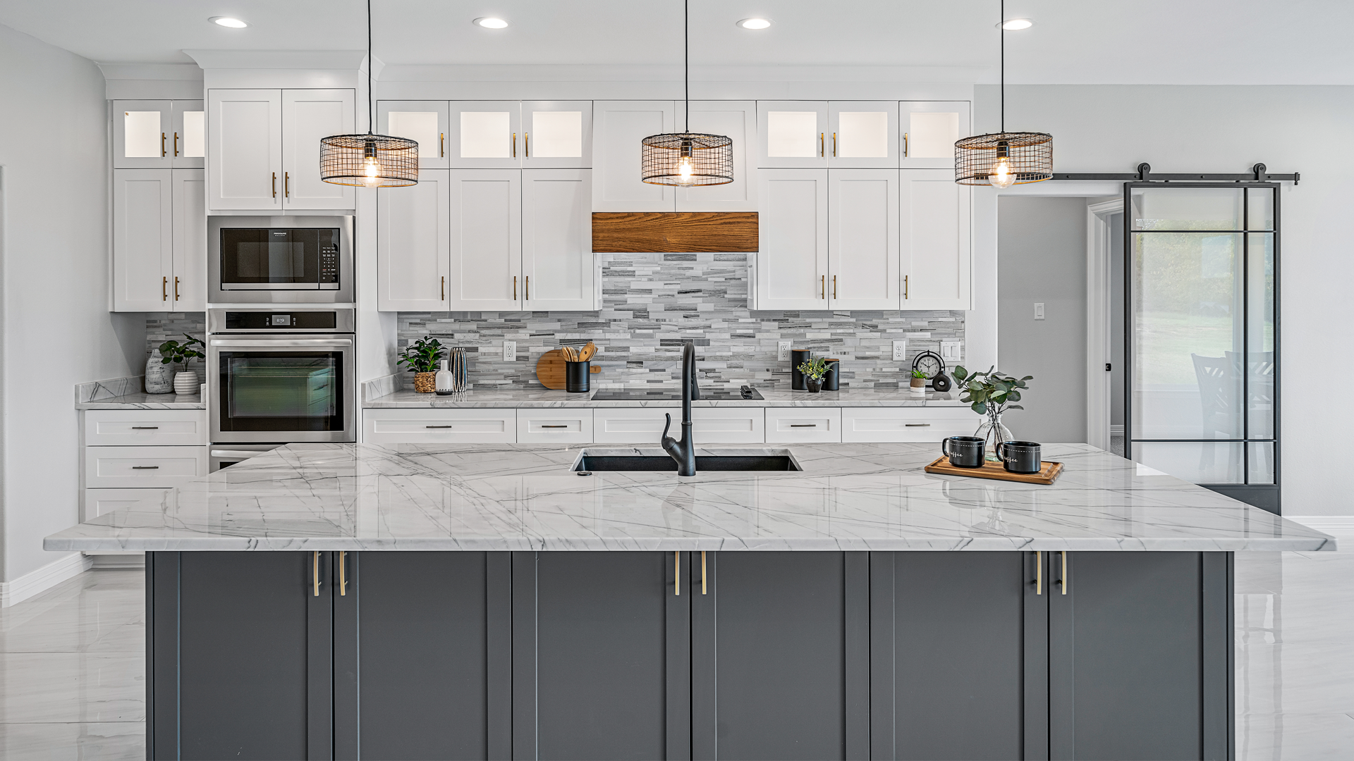 A kitchen with white cabinets and gray cabinets and a large island in the middle.