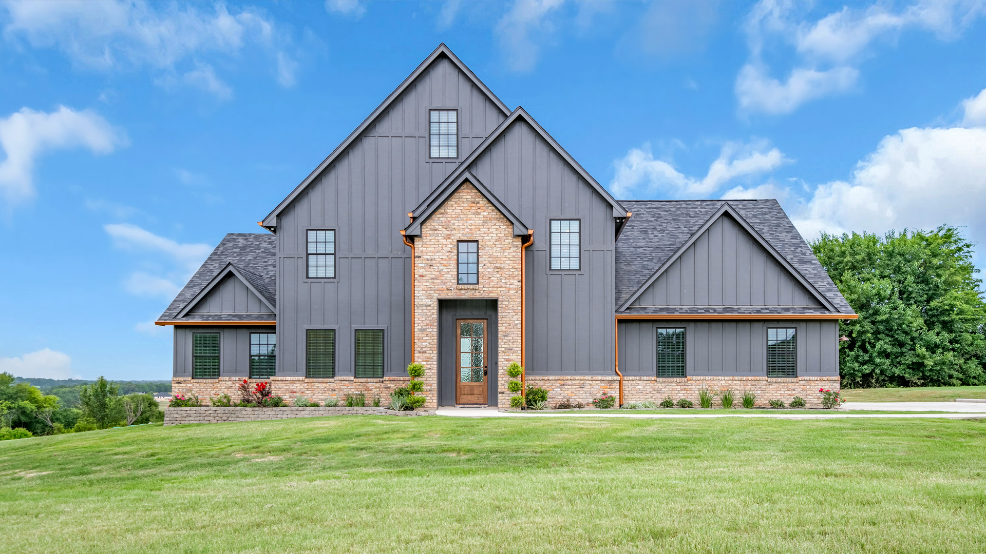 A large house with a lot of windows is sitting on top of a lush green field.