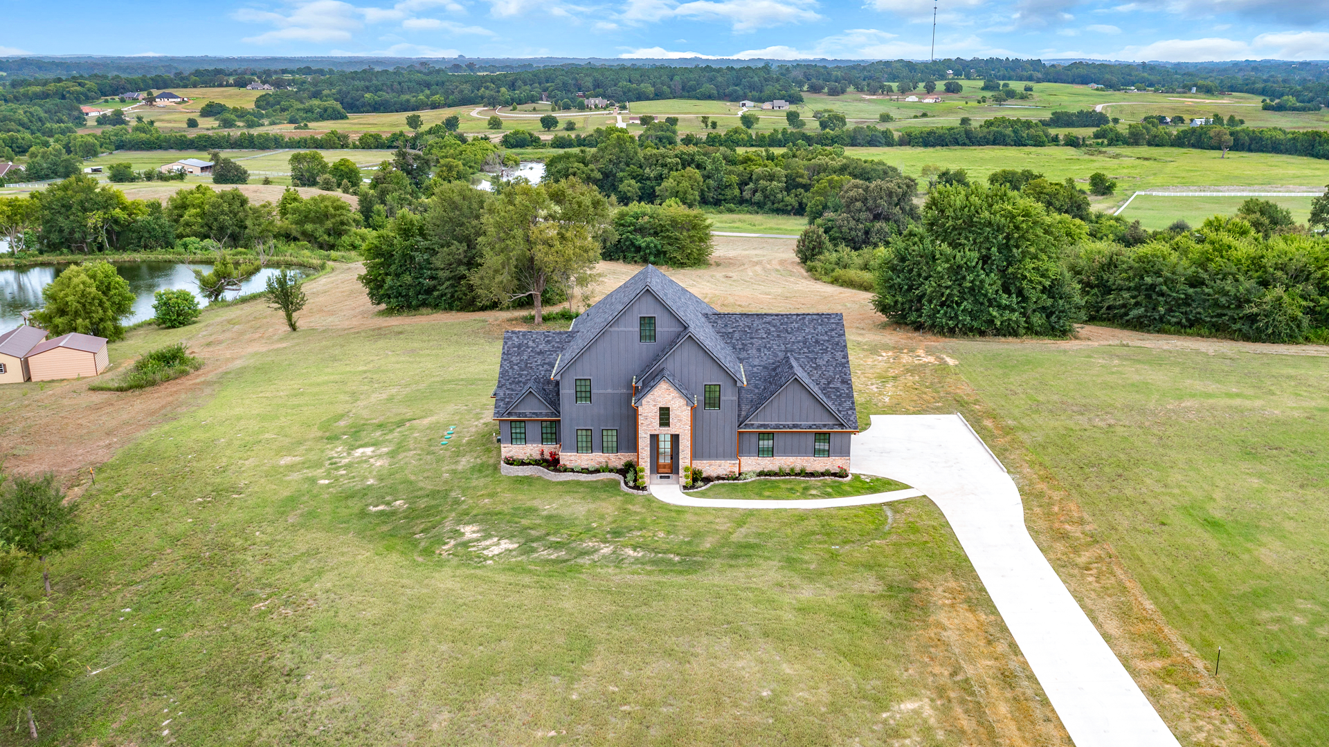An aerial view of a large house in the middle of a lush green field.